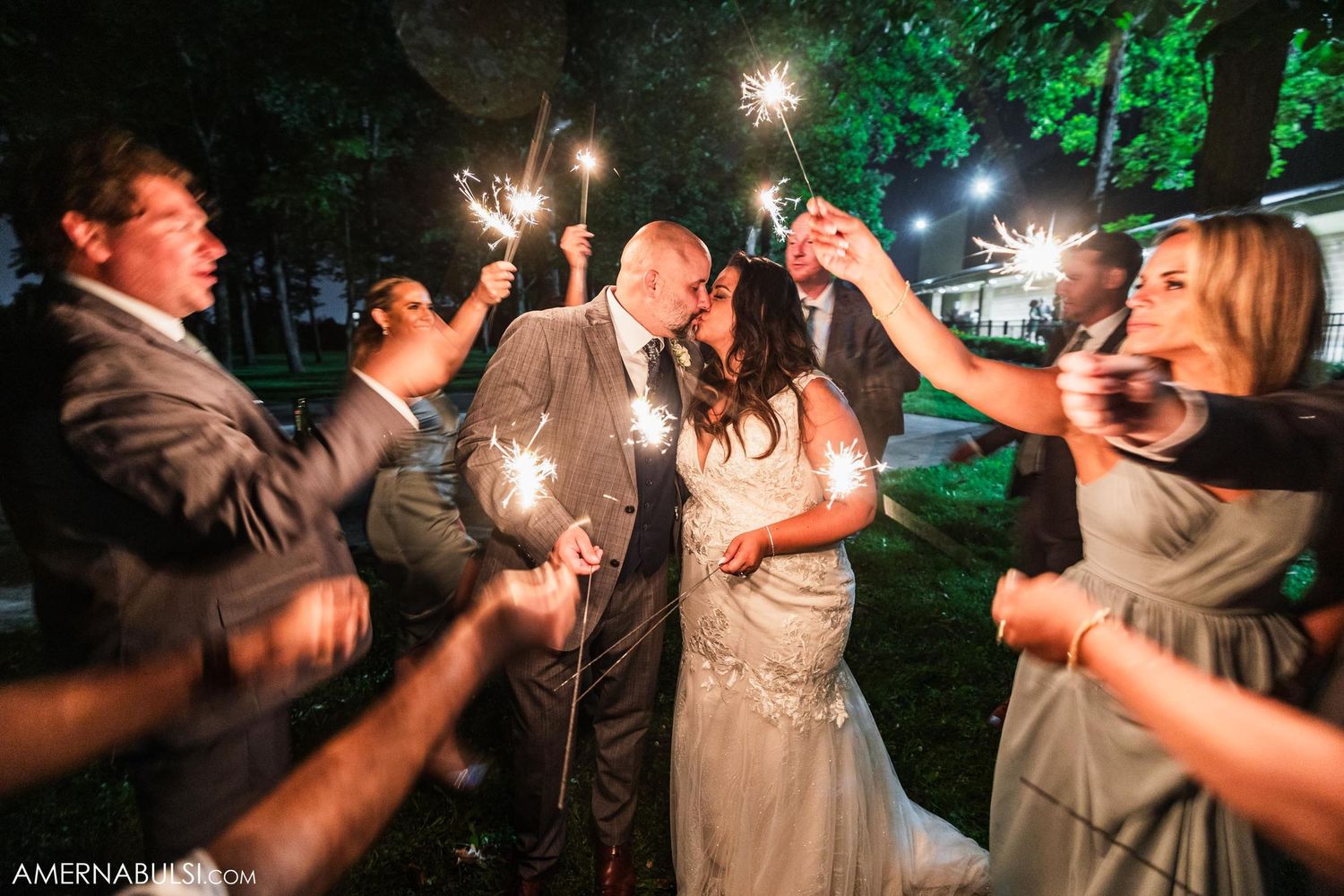 Wedding celebration with sparklers creating a magical nighttime moment between newlyweds and guests.