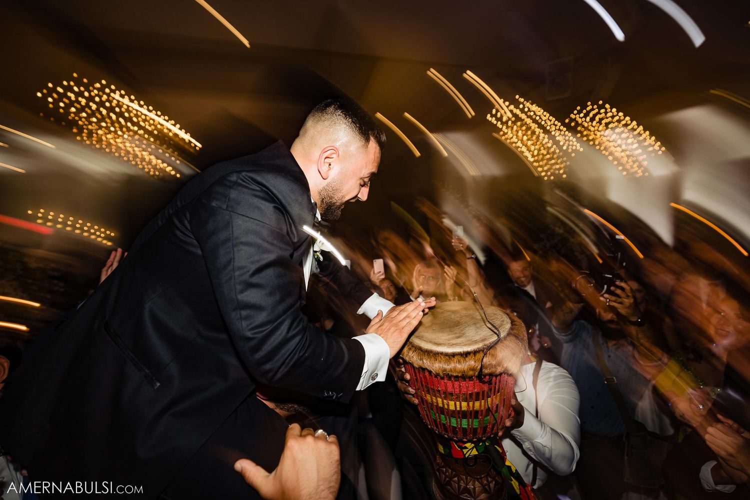 A celebratory dance scene at a wedding reception with motion blur and overhead string lights.