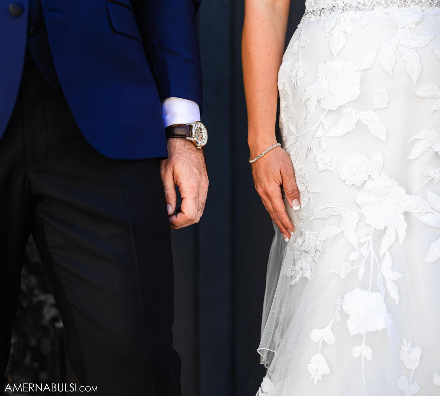 Close-up detail of navy suit jacket and white wedding dress during ceremony.