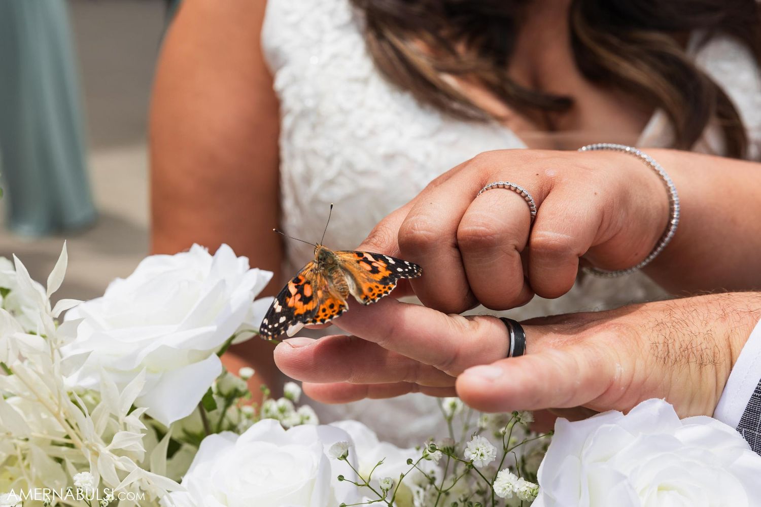 A butterfly lands on a bridal bouquet with white flowers.
