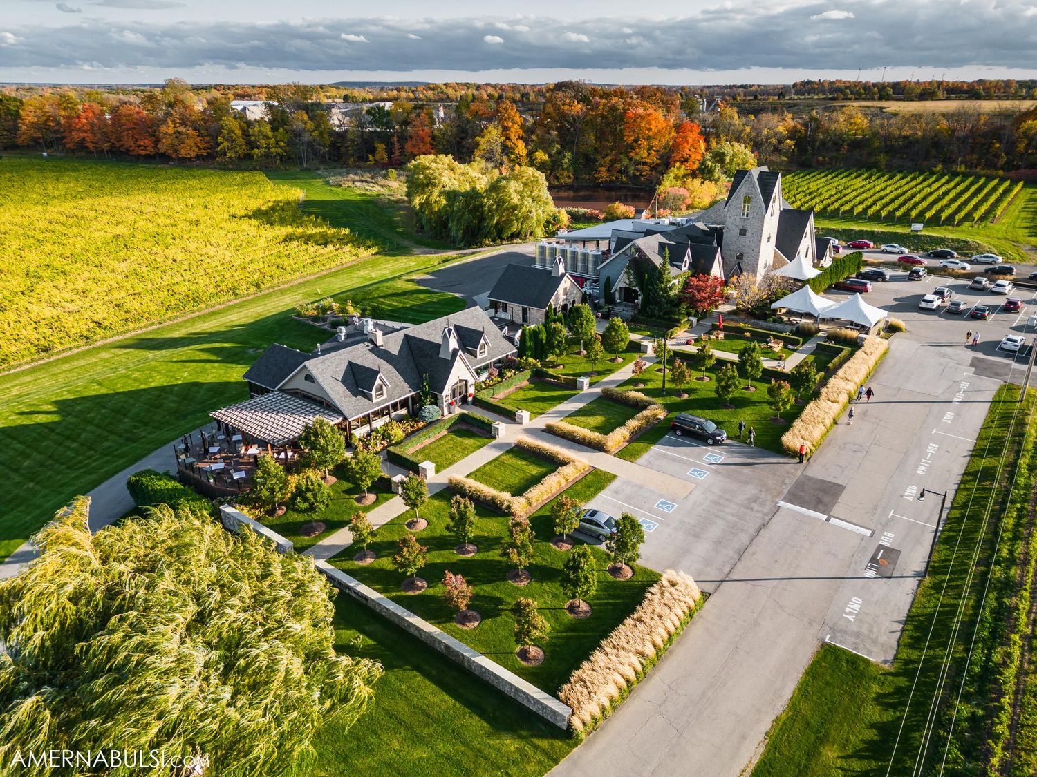 Aerial view of estate with manicured gardens and parking area surrounded by autumn foliage.