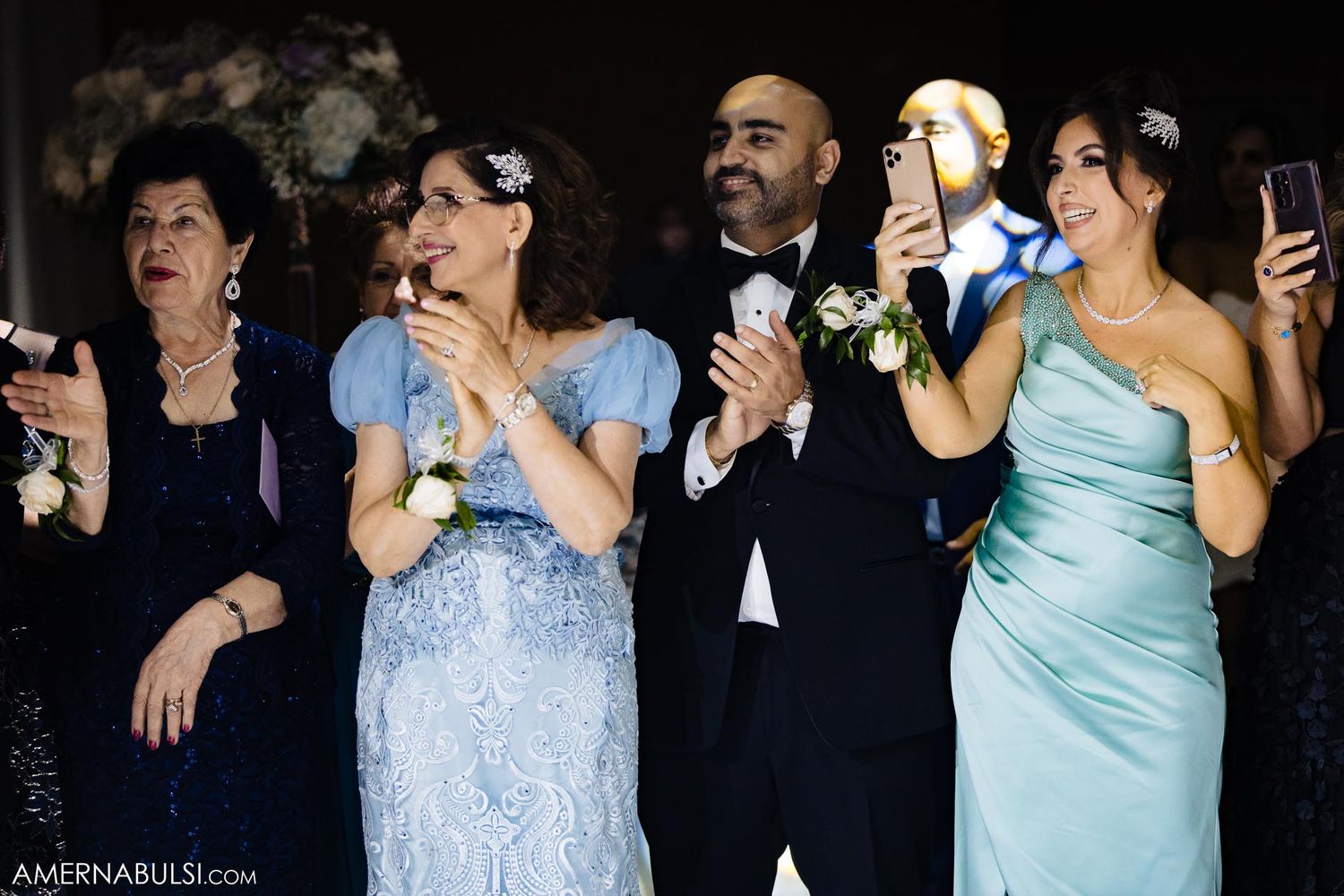 Wedding guests in formal attire reacting emotionally during celebration.