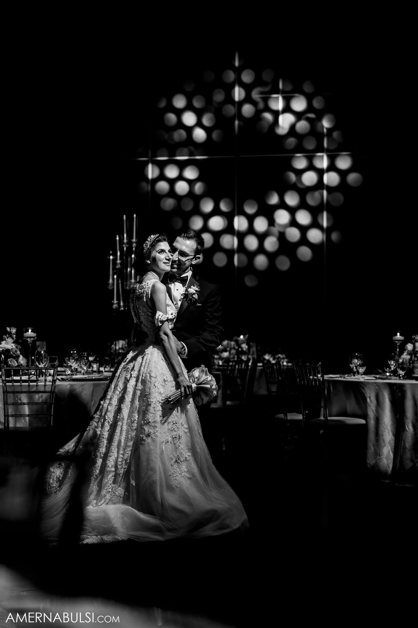 Dramatic black and white wedding dance portrait with geometric light pattern overhead.