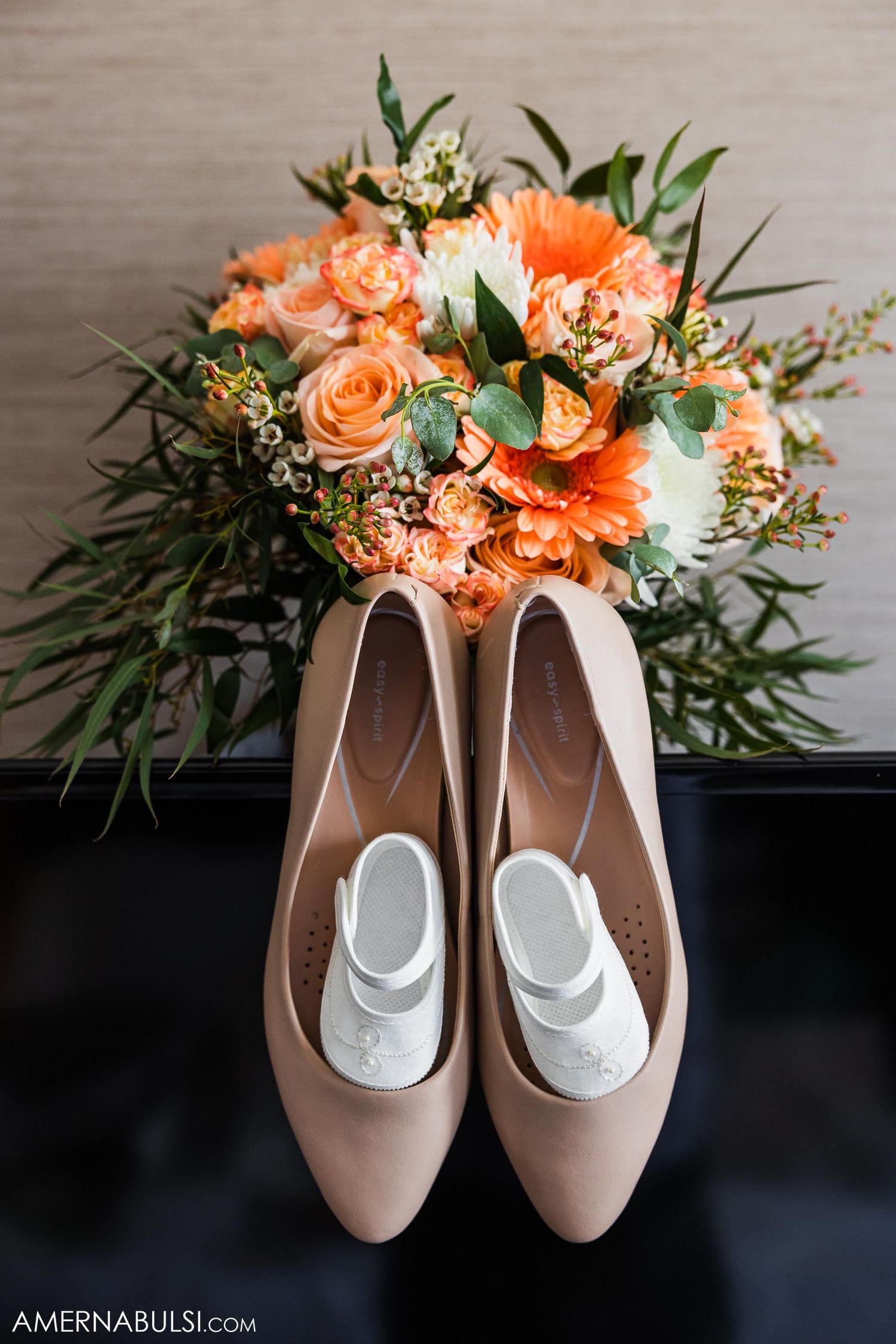 Peach and coral wedding bouquet with roses displayed with nude bridal shoes.
