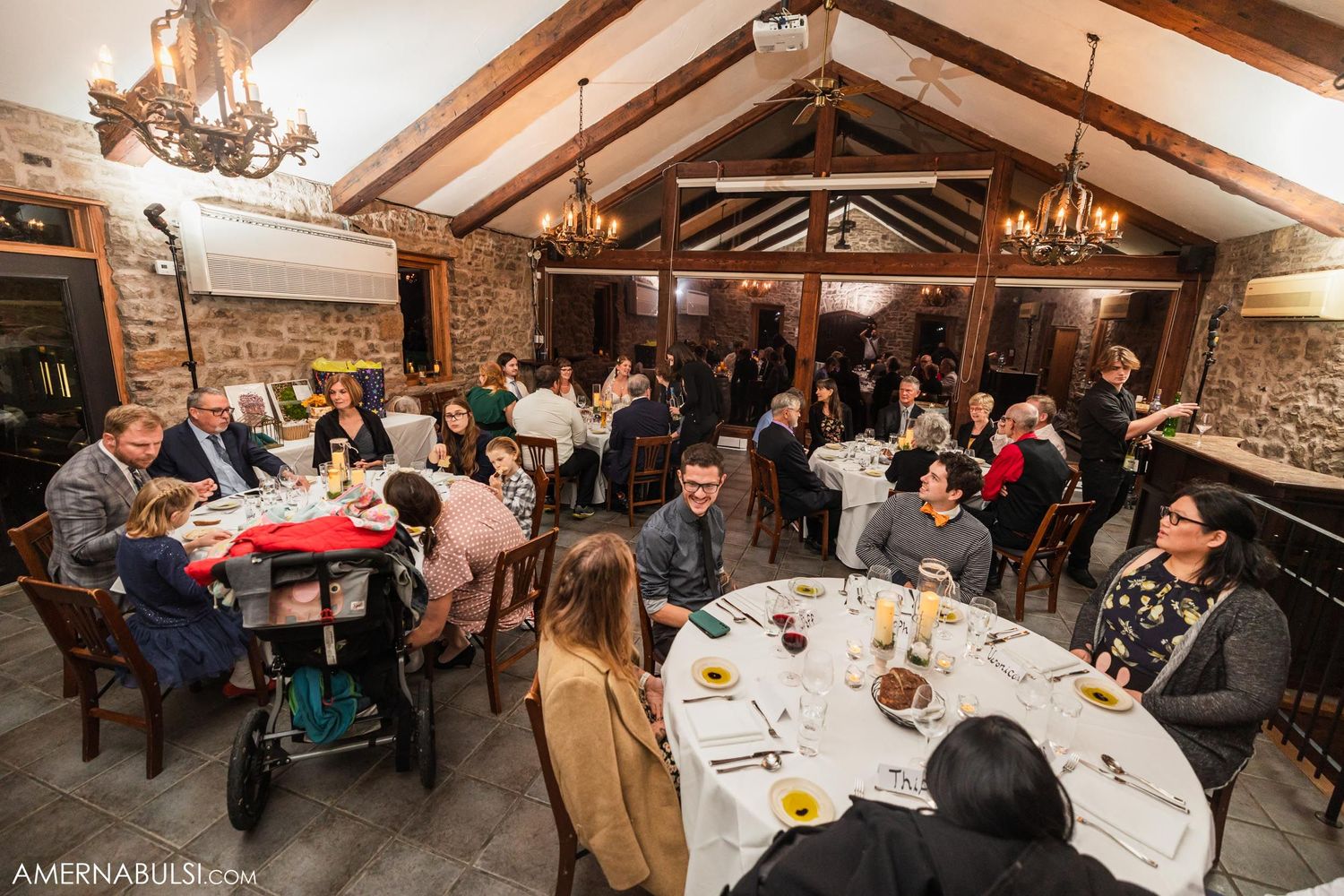 Wide angle view of wedding reception hall with guests seated at round tables.