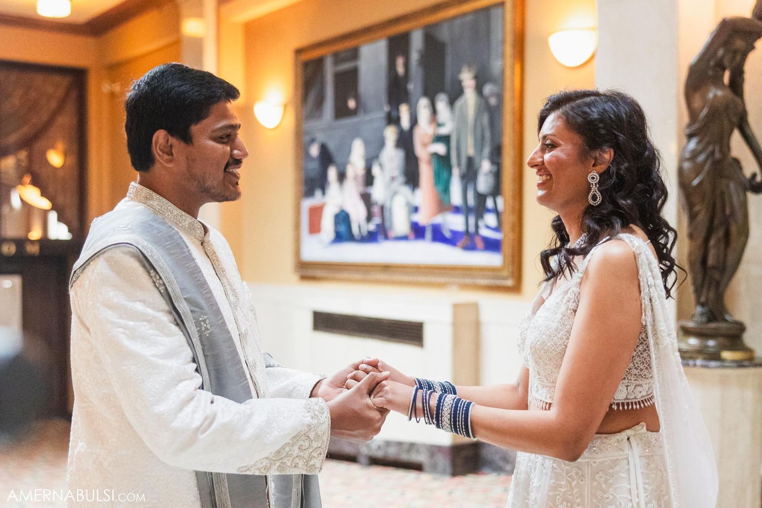 Couple holds hands while sharing intimate moment in formal reception area.