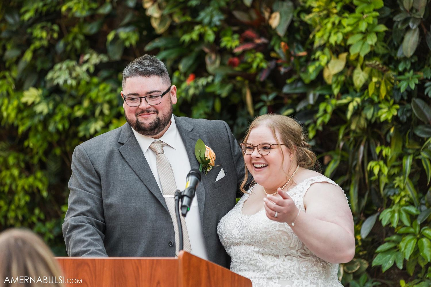 Couple shares a happy moment while giving speeches at their outdoor wedding ceremony.