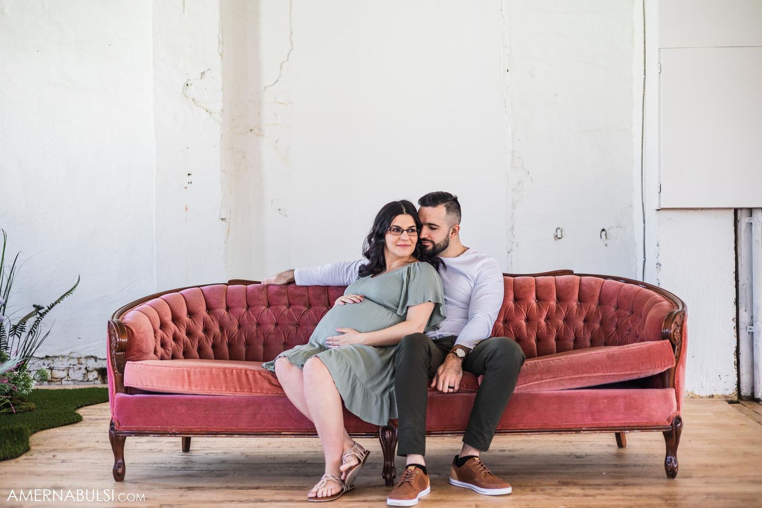 Couple sharing tender moment on vintage pink tufted couch in bright minimalist space.