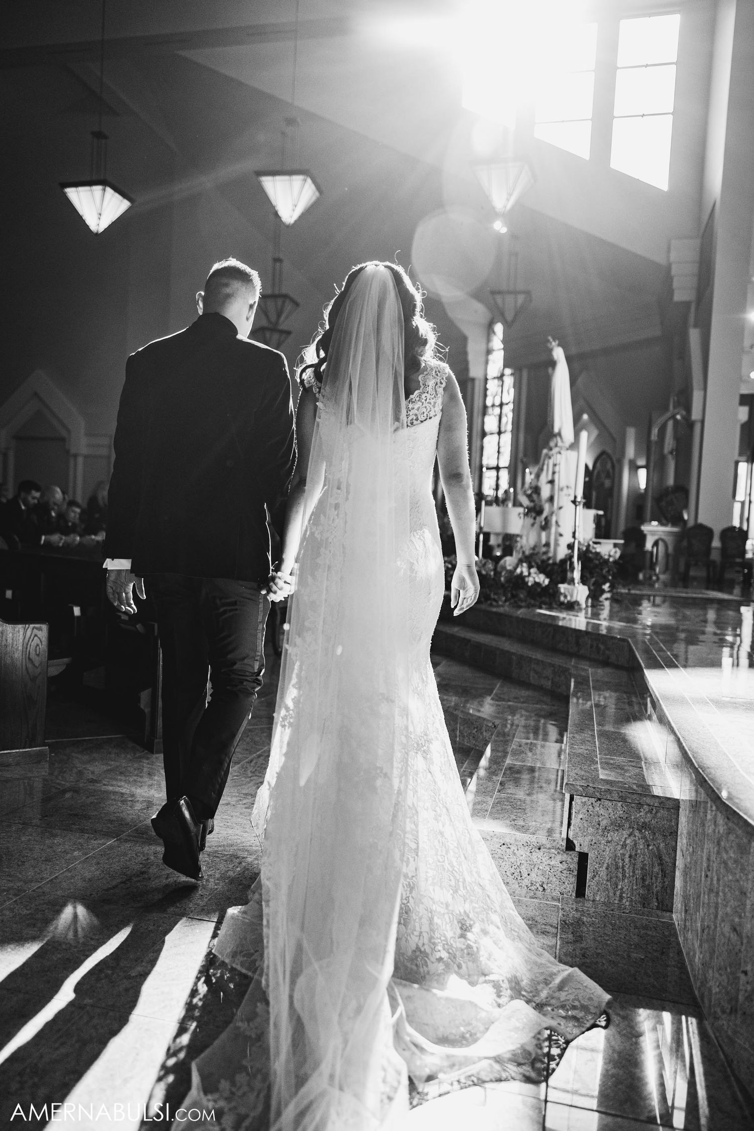 Black and white photo of a couple walking down the aisle during a church wedding ceremony.