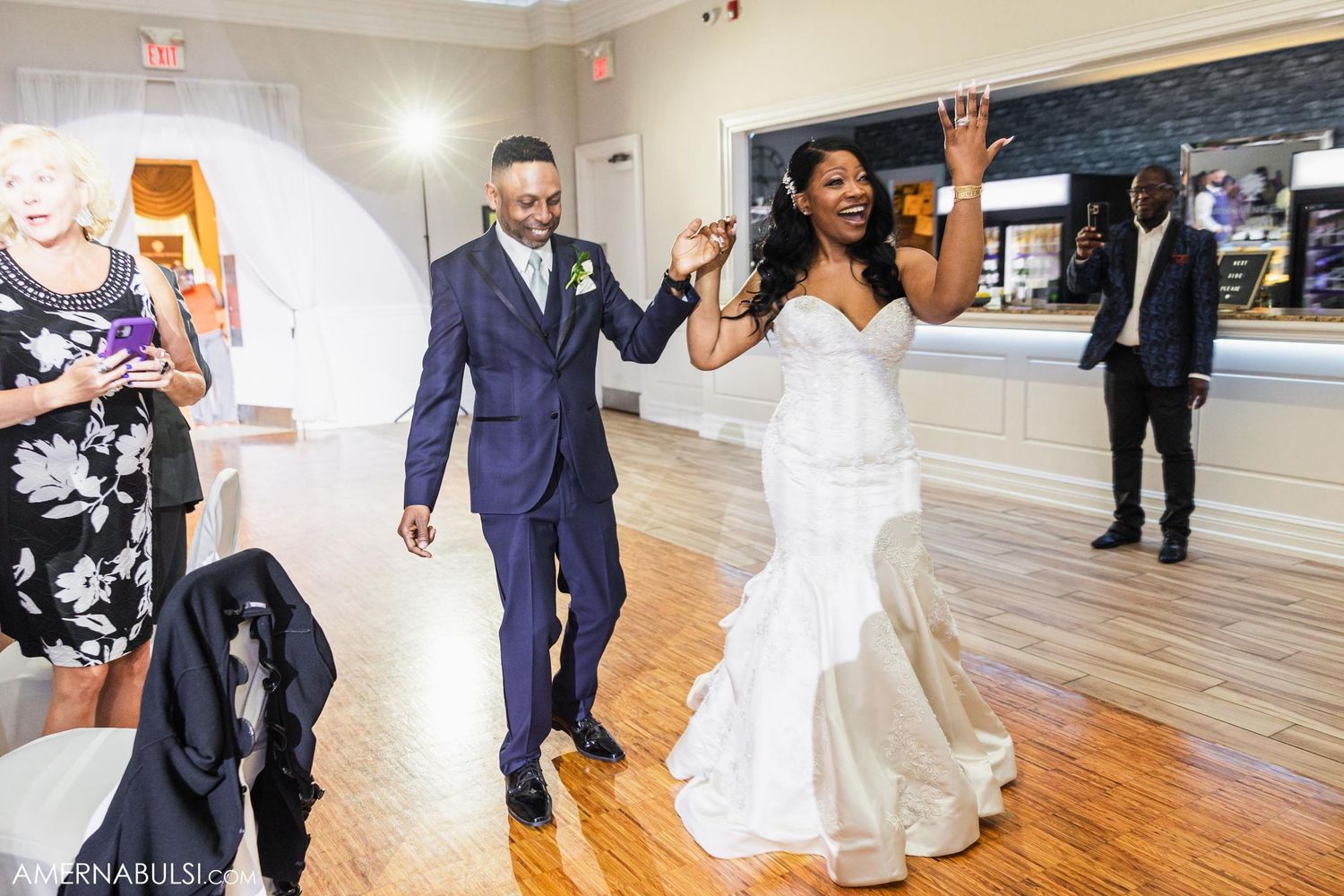 Newlyweds celebrating with joyful dance moves during their wedding reception on wooden dance floor.
