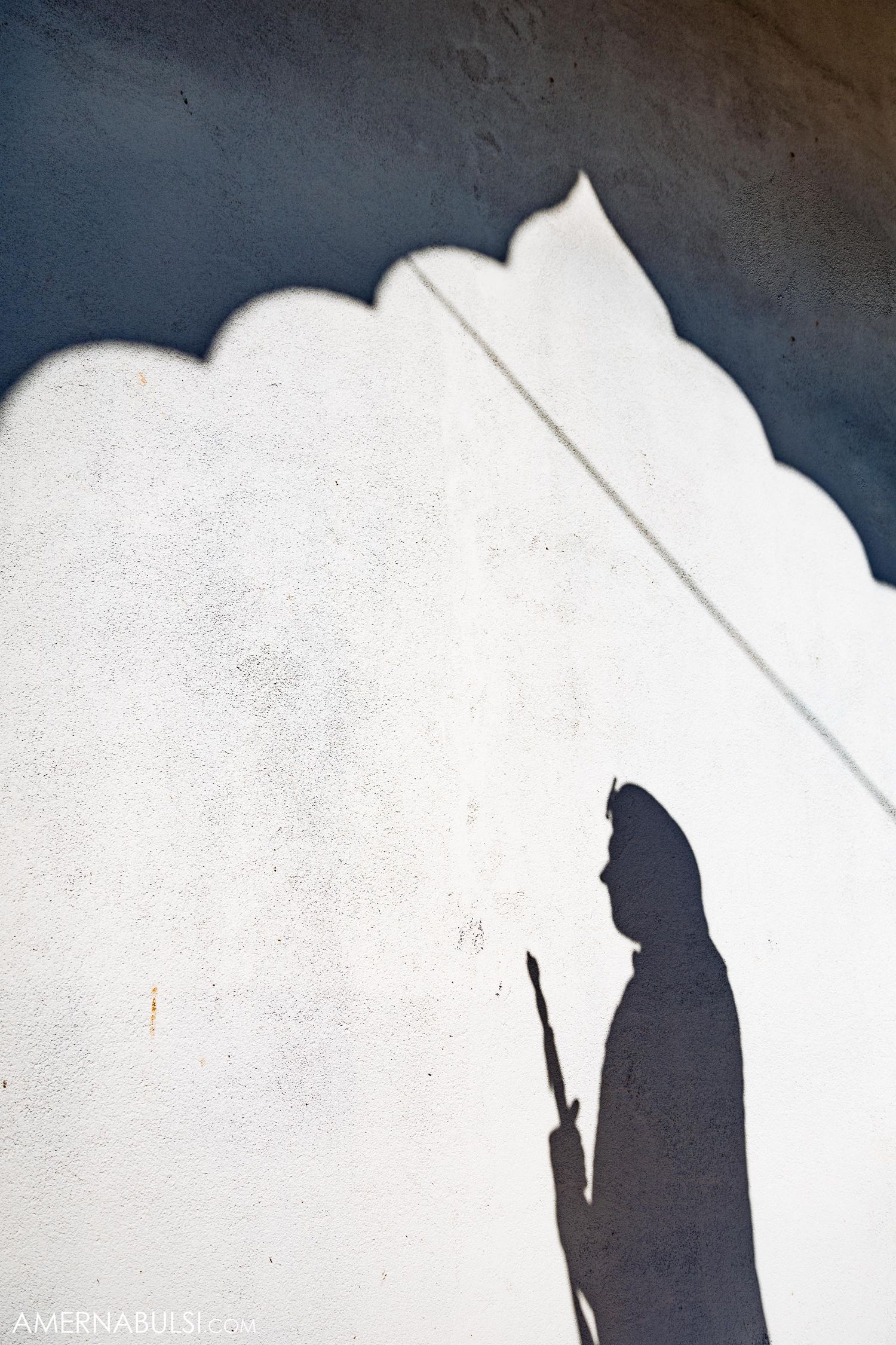 Artistic silhouette of figure against white wall with scalloped architectural details.
