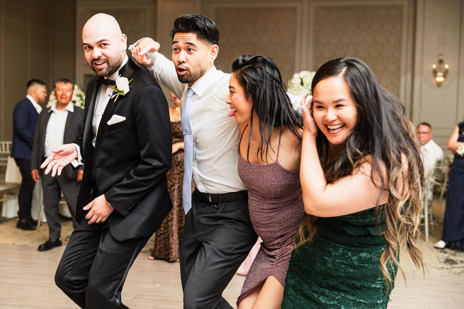 Wedding party members dance together with expressive joy at the reception.