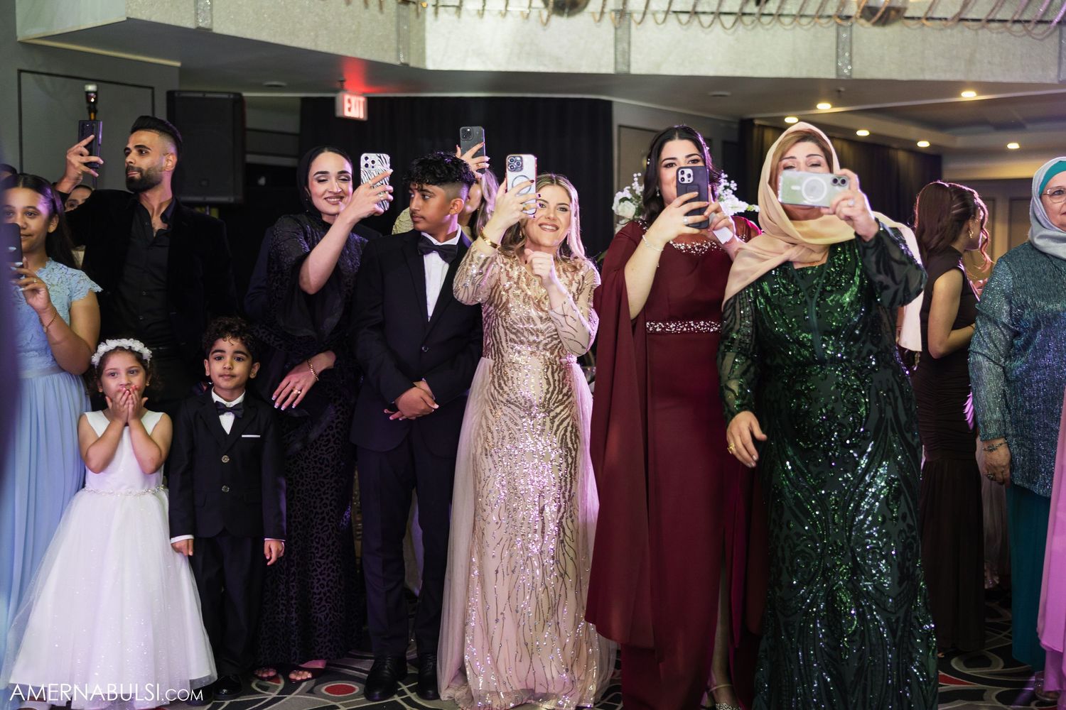 Wedding guests in formal attire celebrating on dance floor with festive atmosphere.