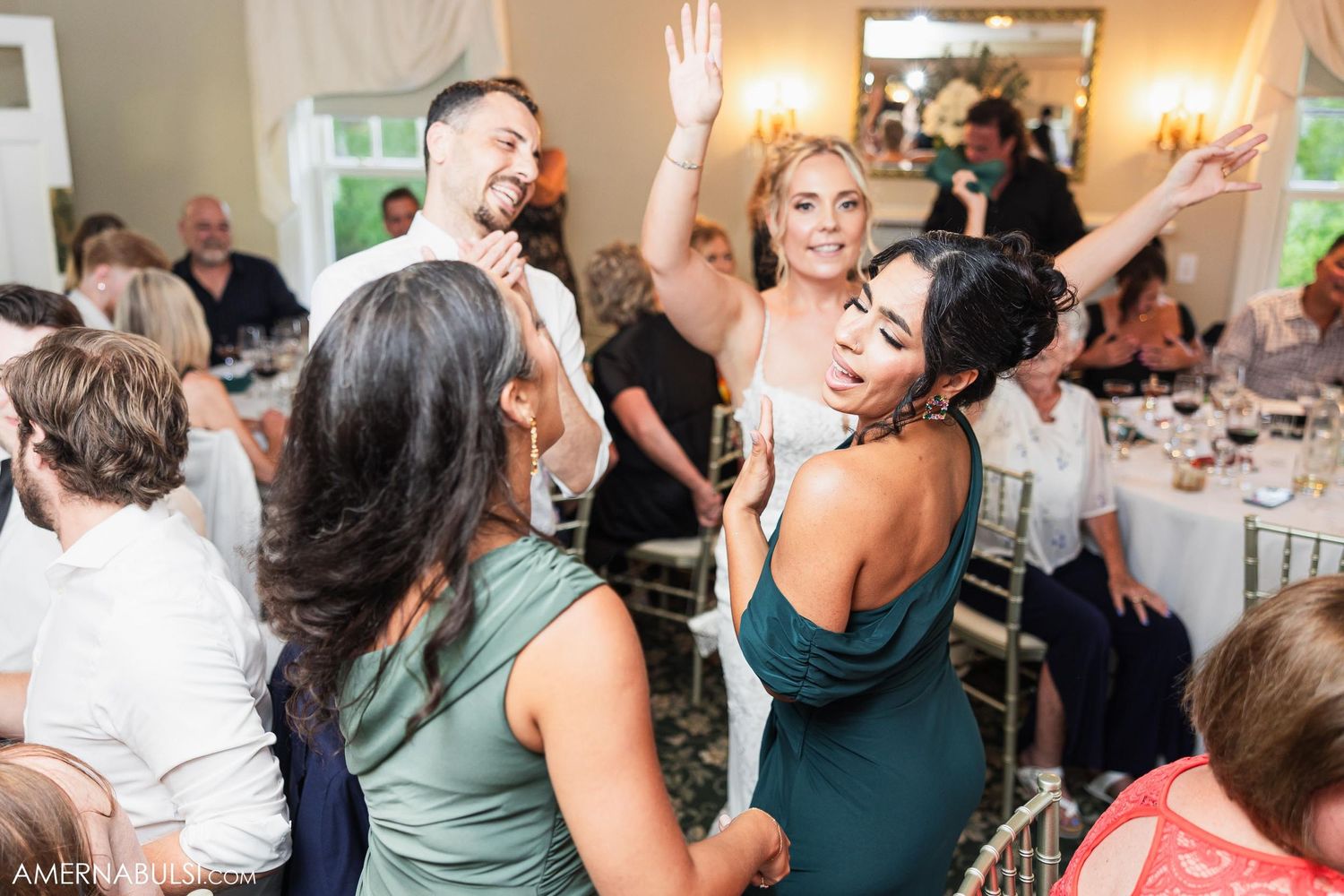 Wedding guests dancing and celebrating at an elegant indoor reception.