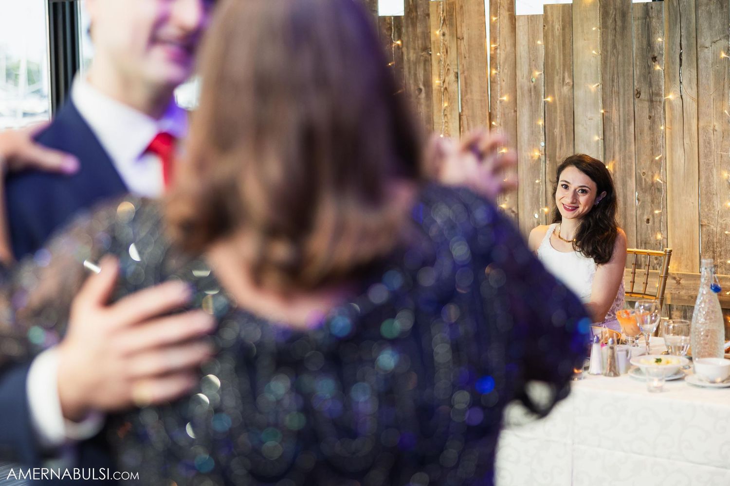 Candid wedding reception photo showing guests through rustic wooden decor.