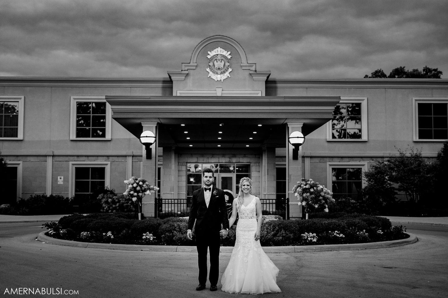 Dramatic black and white panorama of a wedding venue exterior with cloudy skies and classic architecture.
