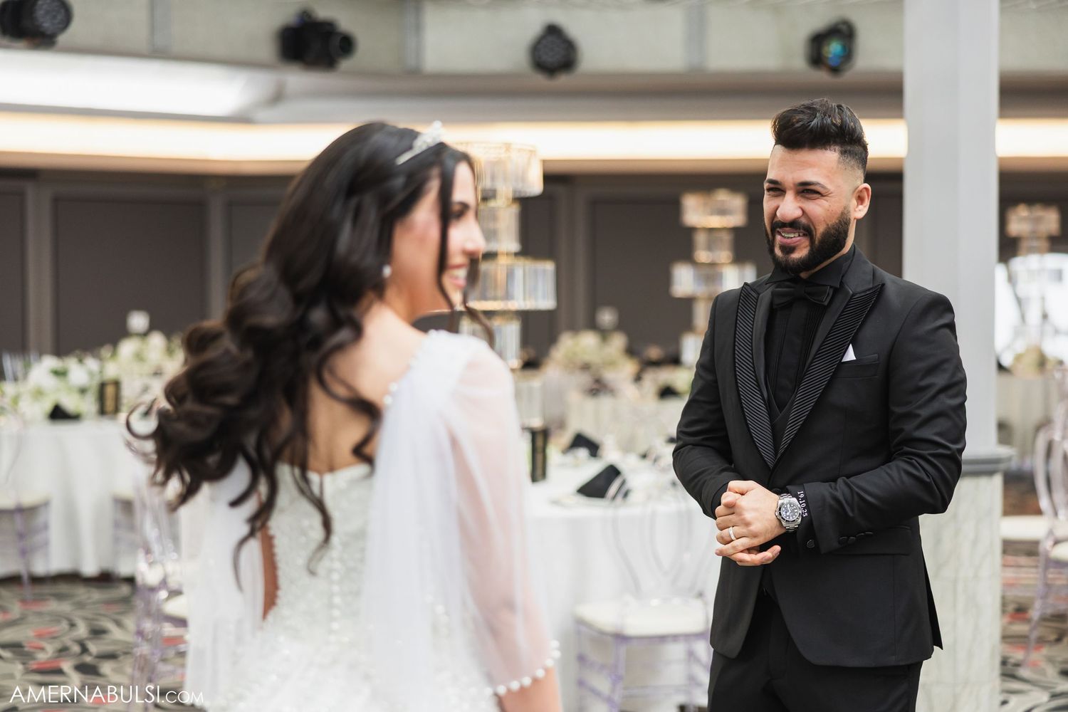 Wedding couple shares intimate first look moment in a bright indoor reception space.