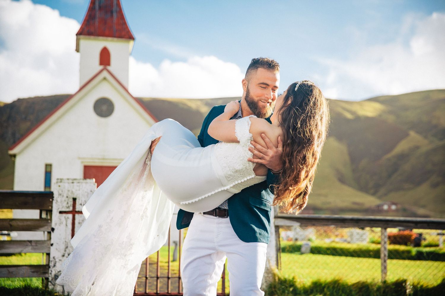 Wedding couple embraces against scenic mountain landscape during sunset photoshoot.