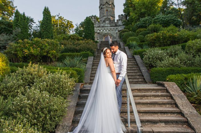 Garden wedding portraits on stone steps surrounded by lush greenery and flowers.