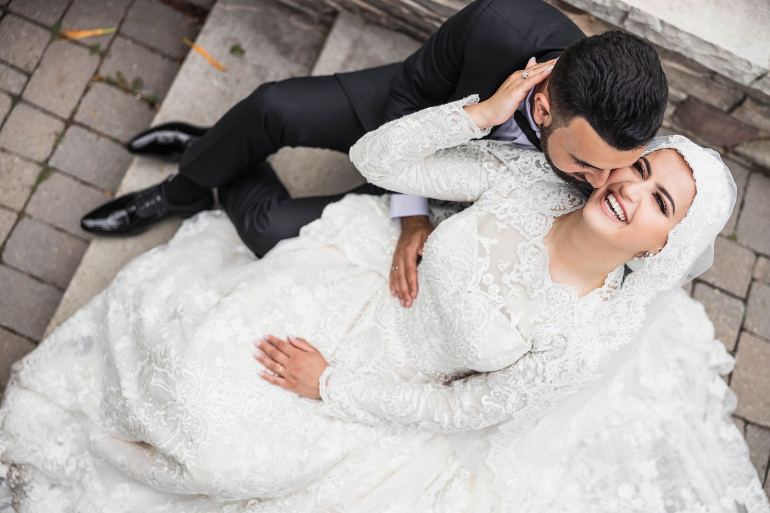 Overhead view of couple in wedding attire on stone pavement.