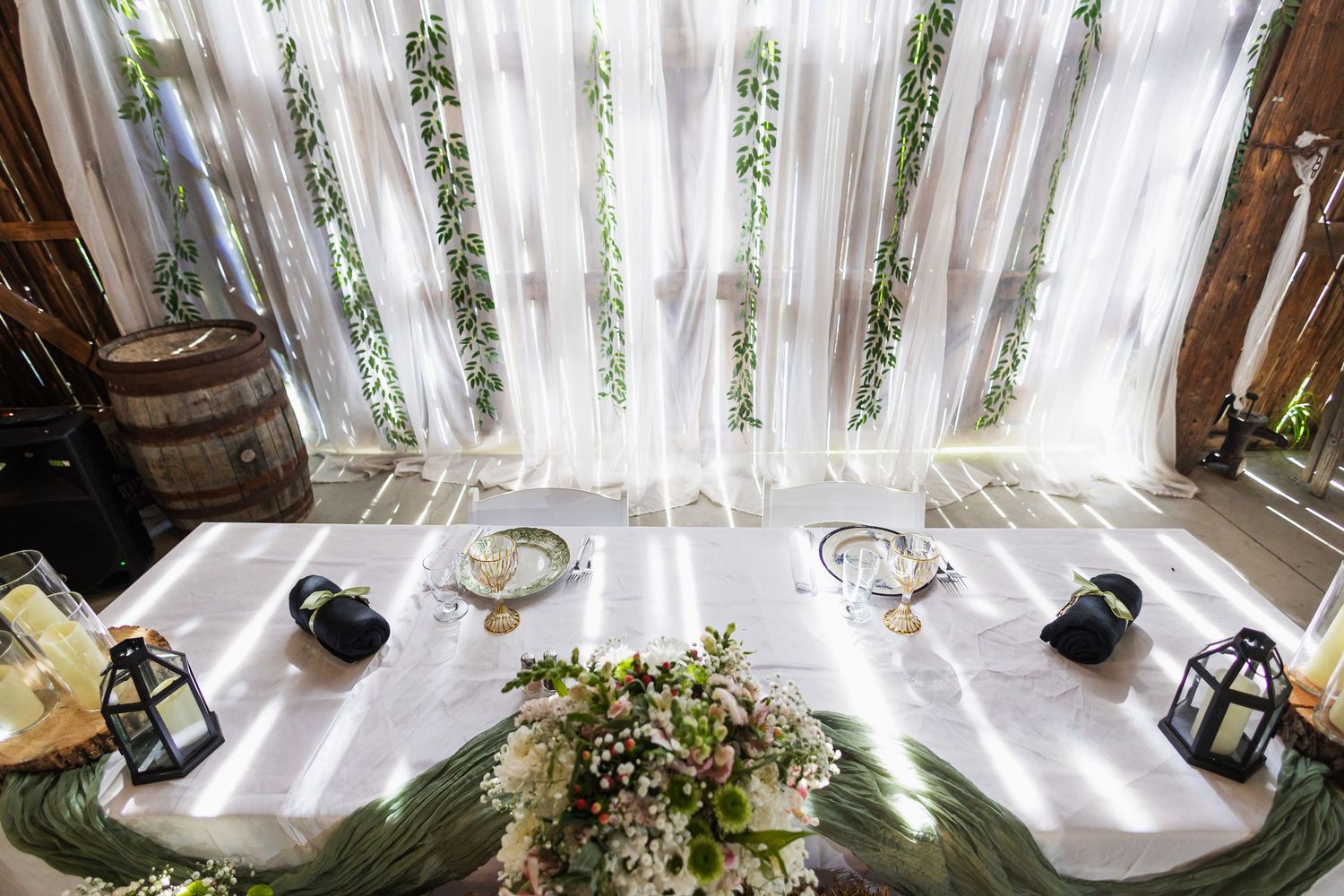 Aerial view of elegant wedding head table with lanterns, floral arrangements, and white draping backdrop.