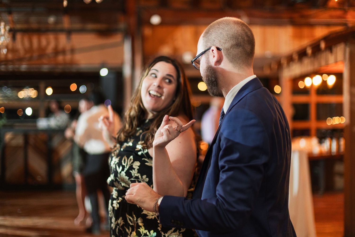 Couple sharing a joyful moment while slow dancing at a rustic wedding reception venue.