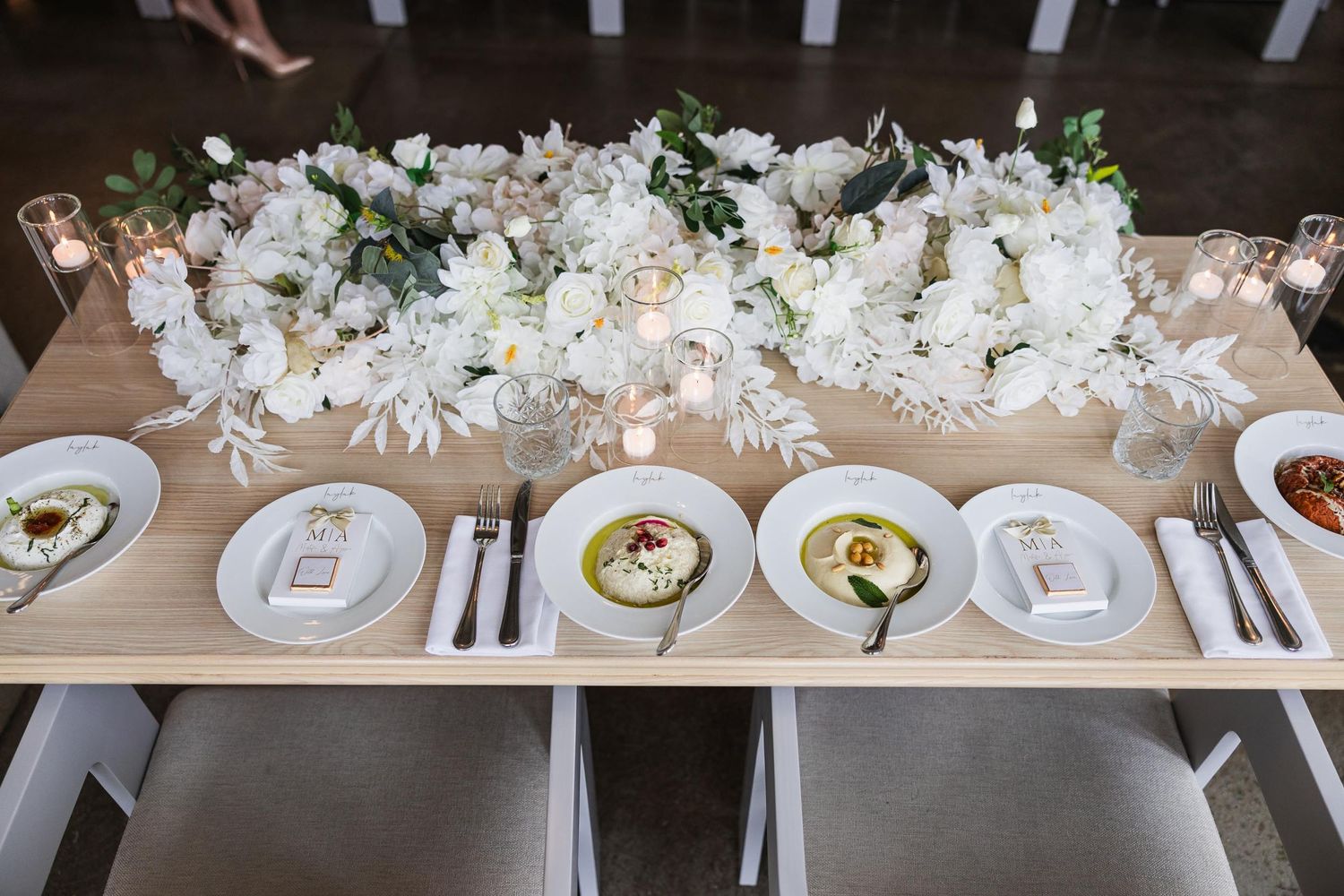 Elegant table setting with white floral centerpiece and formal place settings.