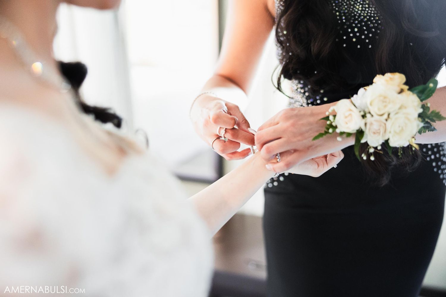 Close up of hands with white flowers during wedding preparation.