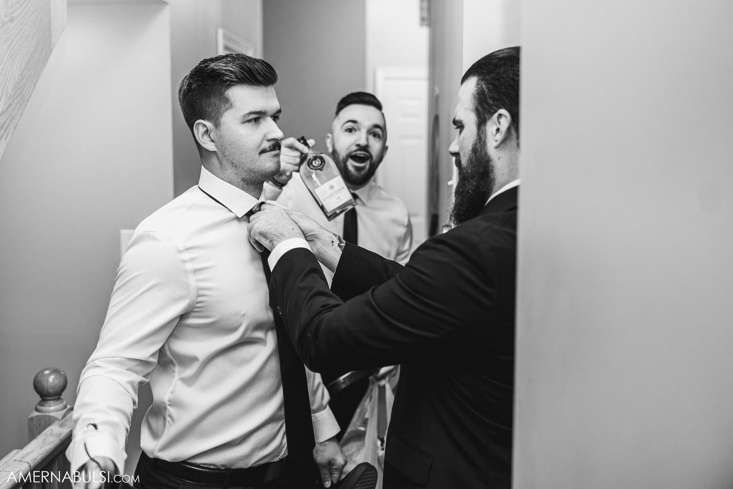 Three people laughing and adjusting clothing in hallway.