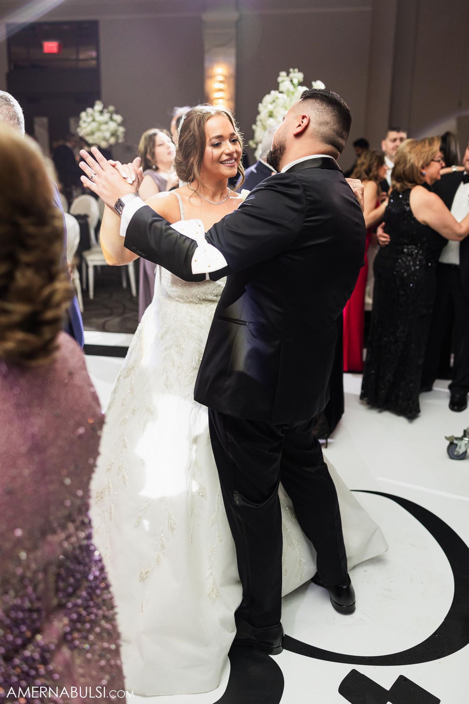 Couple dances on decorated ballroom floor during wedding reception.