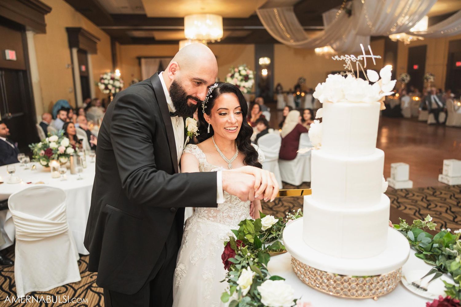 Bride and groom cutting their elegant white wedding cake together at their reception.