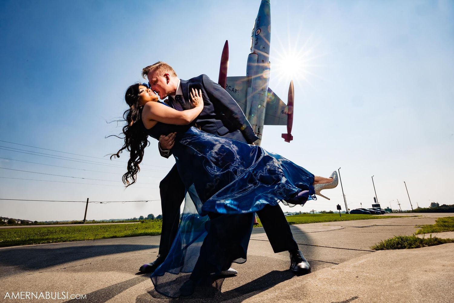 A dramatic dip pose between a couple on an airfield with planes in the background.