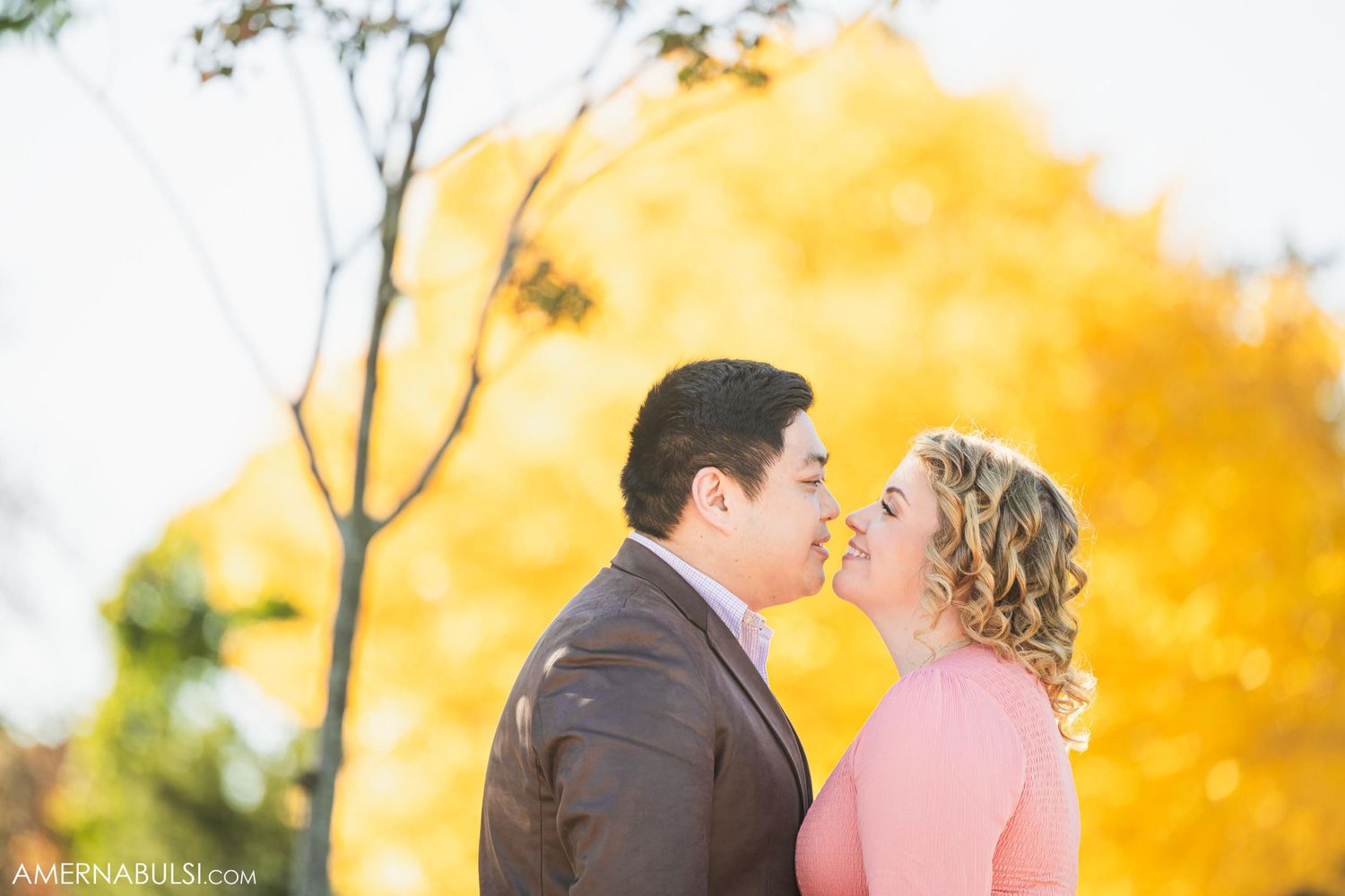 Romantic couple about to kiss with golden autumn foliage in background.