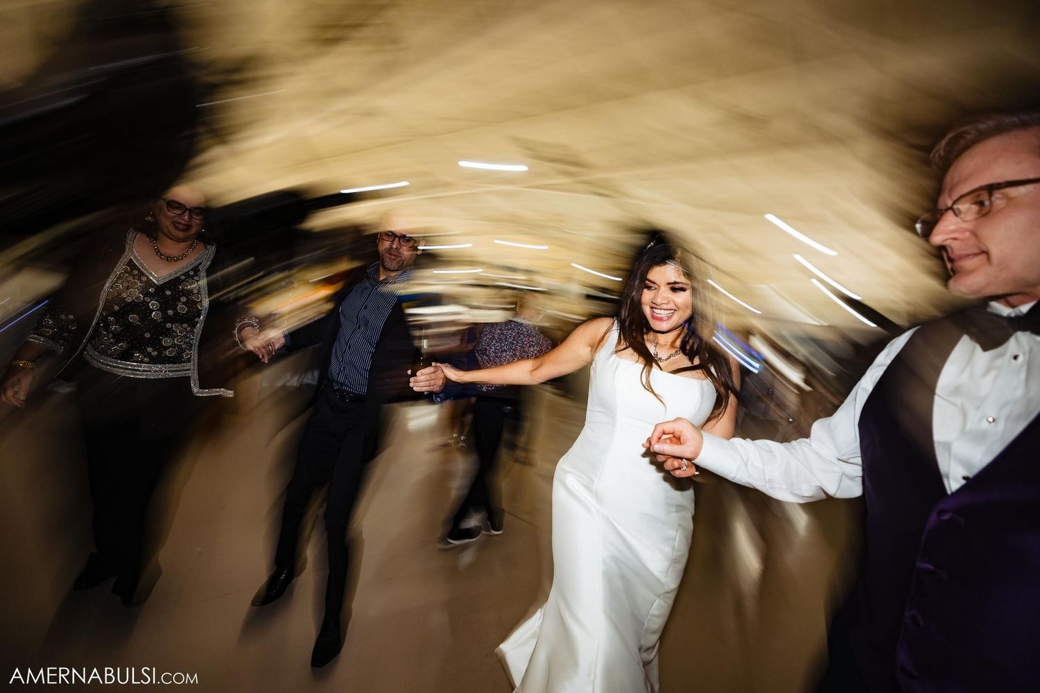 Wedding celebration captured with creative motion blur showing bride dancing with guests.