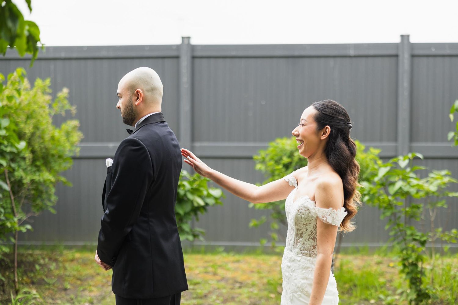 A bride reaching out to touch her groom's shoulder during their first look moment.