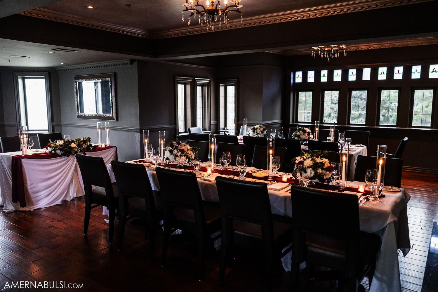 Elegant dark wood dining room with long tables set for a formal wedding reception.