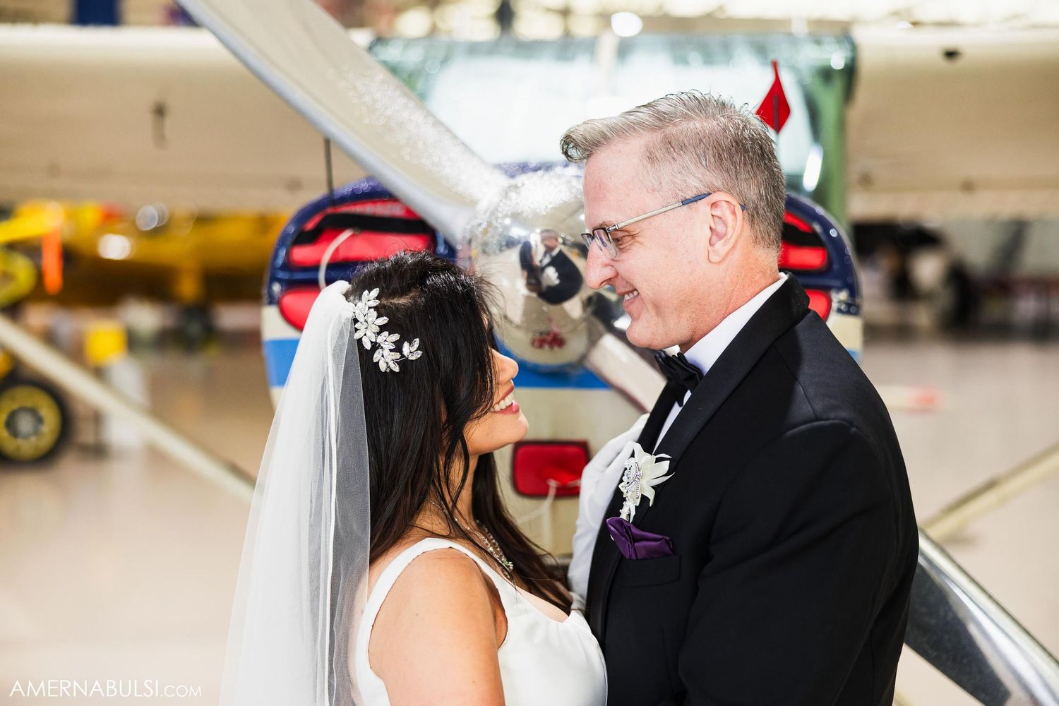 A tender wedding moment captured in front of a vintage aircraft.