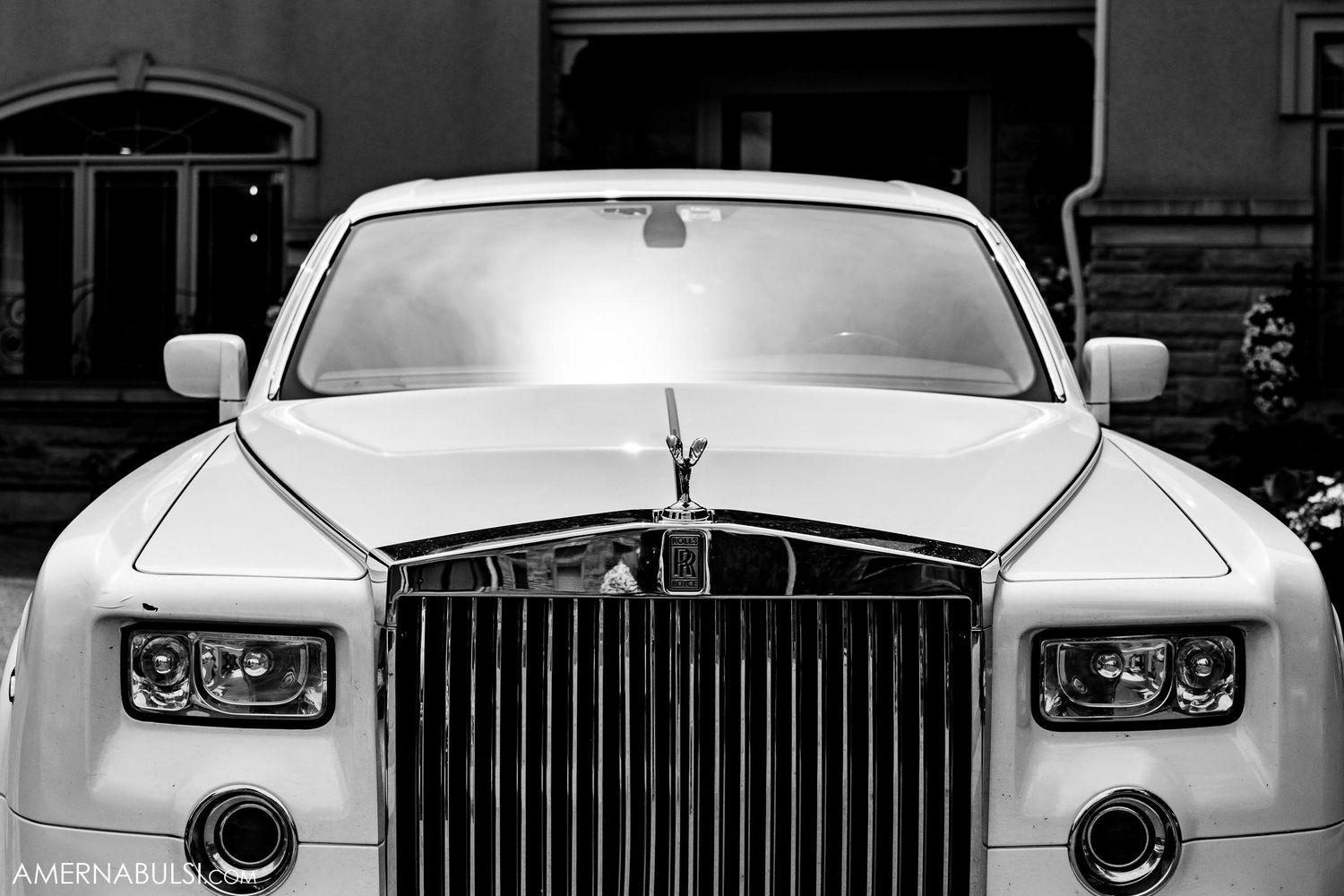 Front view of a luxury white Rolls Royce with its distinctive grille and Spirit of Ecstasy ornament.