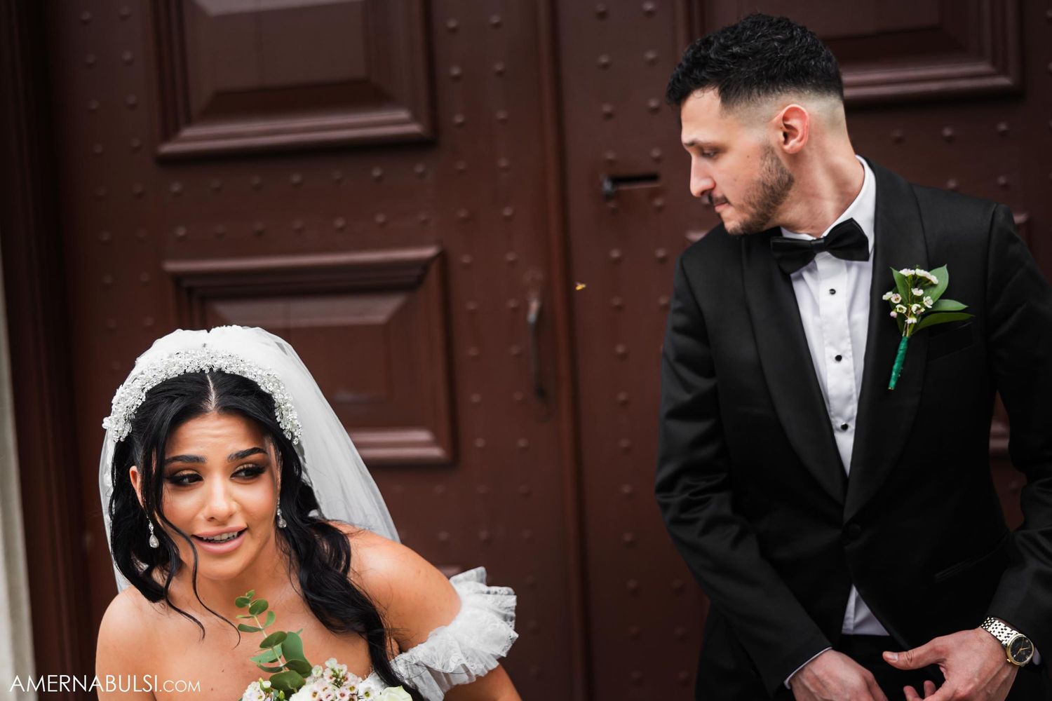 Candid wedding moment captured in front of vintage wooden doors.