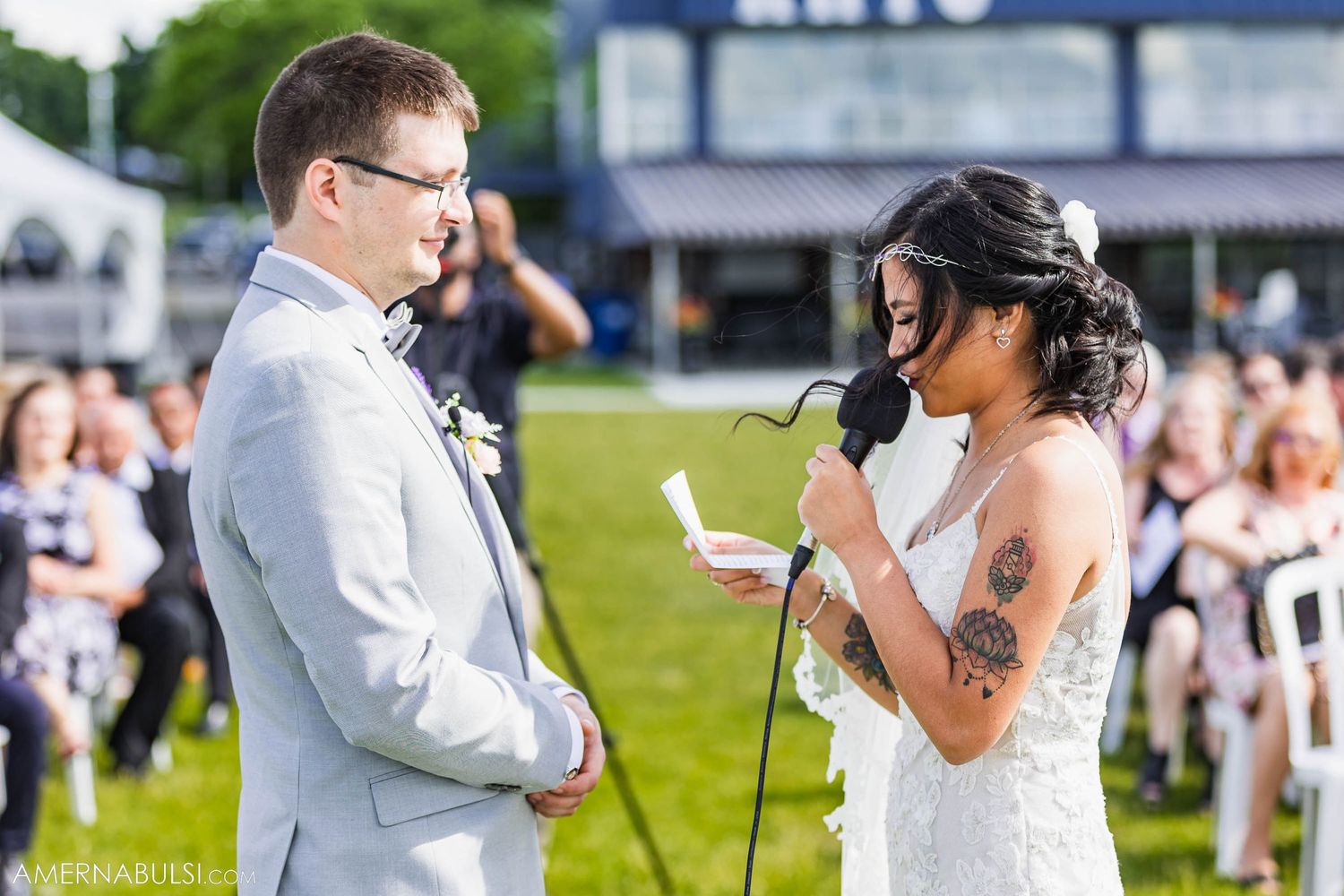 Couple exchanges vows during outdoor wedding ceremony with guests watching.