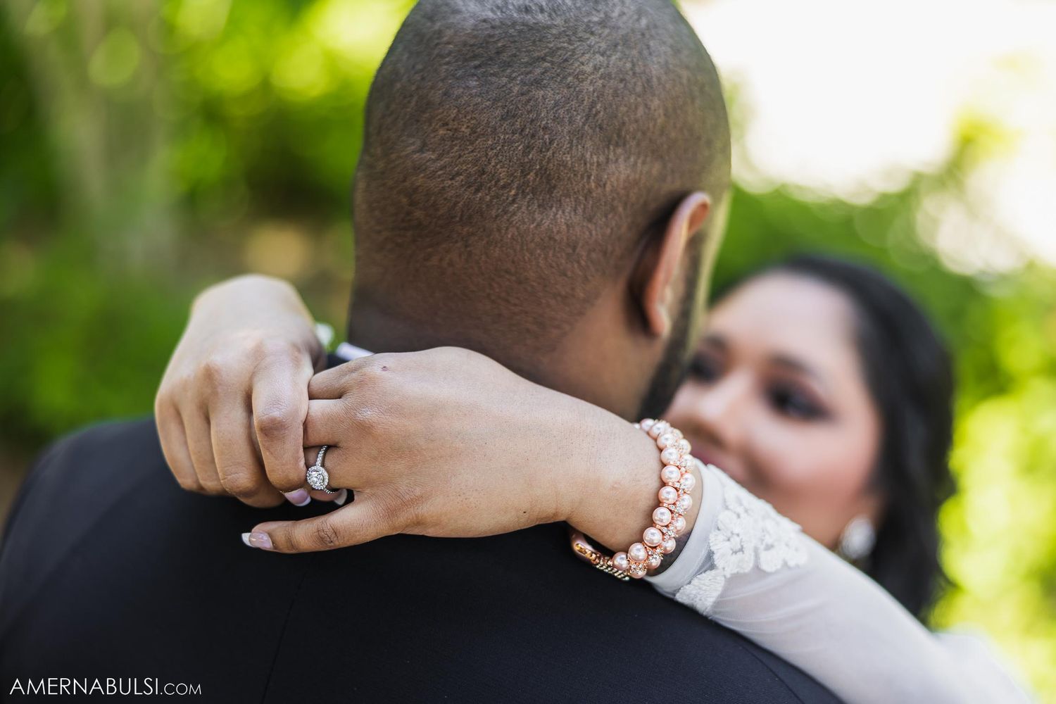 Close up of embracing couple showing off wedding jewelry and lace sleeves.