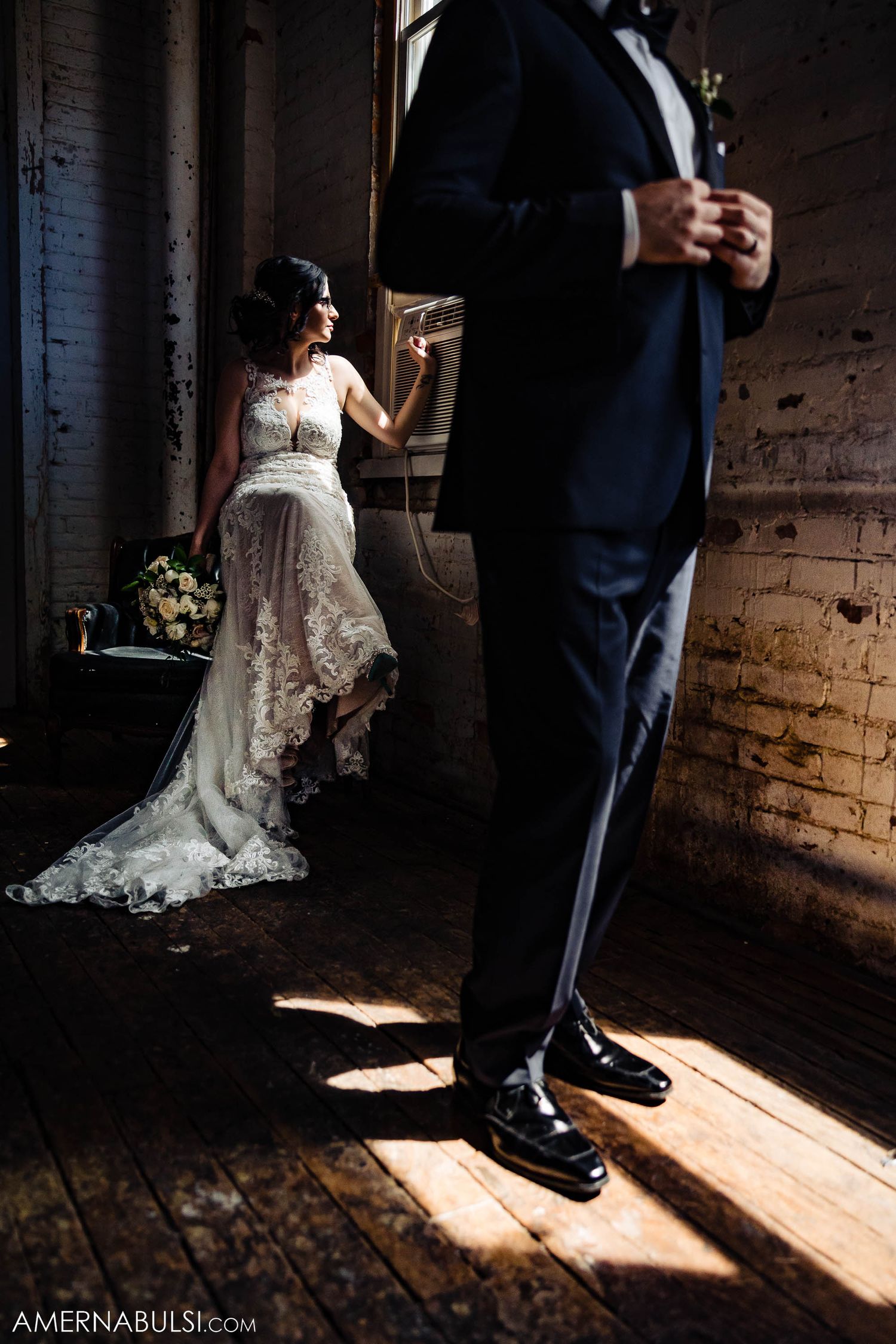 Artistic wedding photo showing silhouette and lace dress details in dramatic lighting.