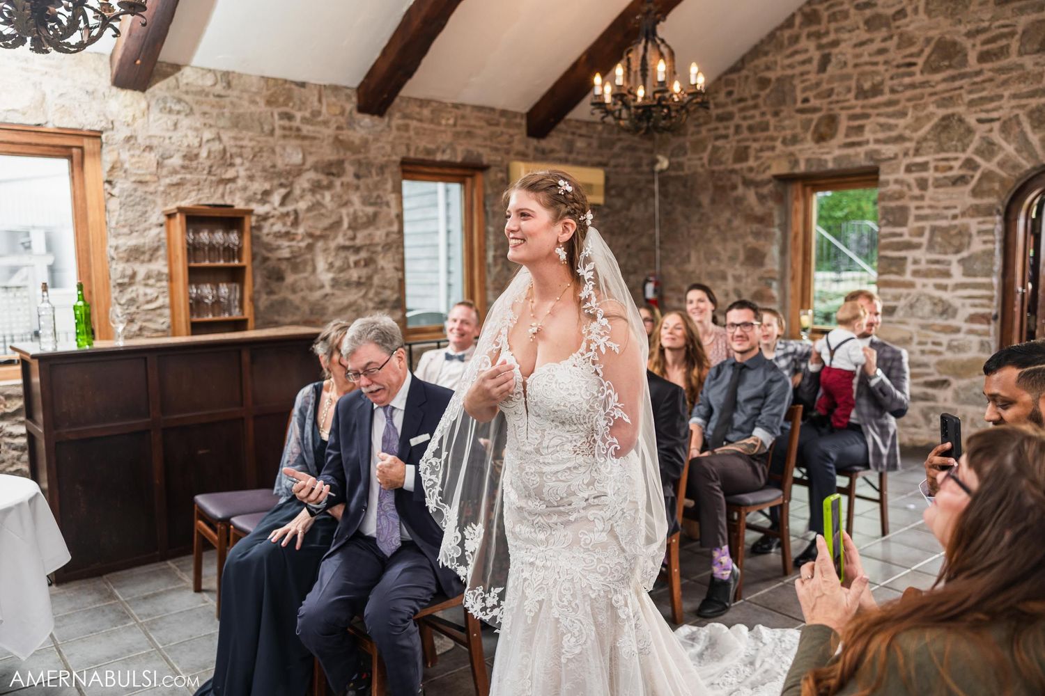 Wedding celebration inside rustic stone venue with exposed beam ceiling and chandelier.