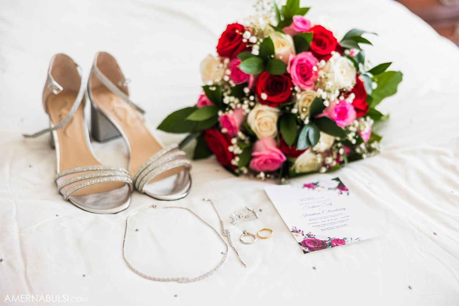Wedding accessories including silver heels and a vibrant red and pink bouquet.