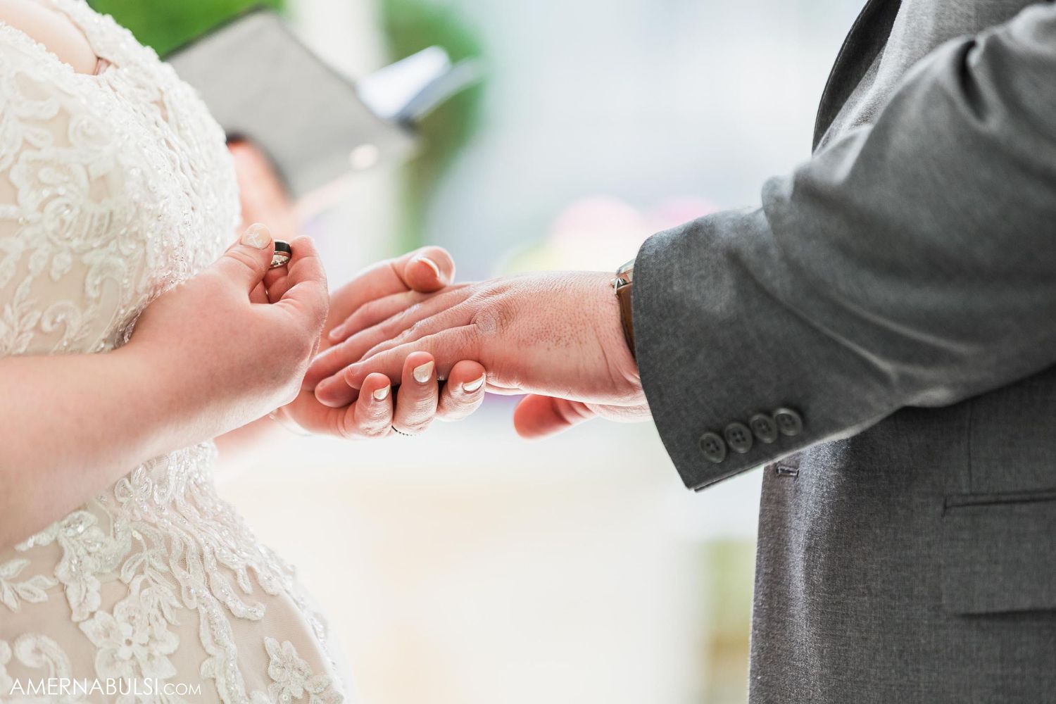 Close-up shot of hands exchanging rings during wedding ceremony.