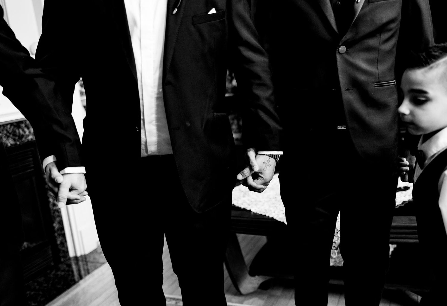 Black and white detail shot of formal suits and dresses during a wedding ceremony.