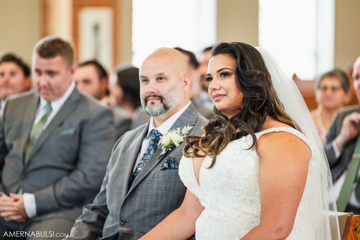A newlywed couple sits together during their wedding ceremony in a church.