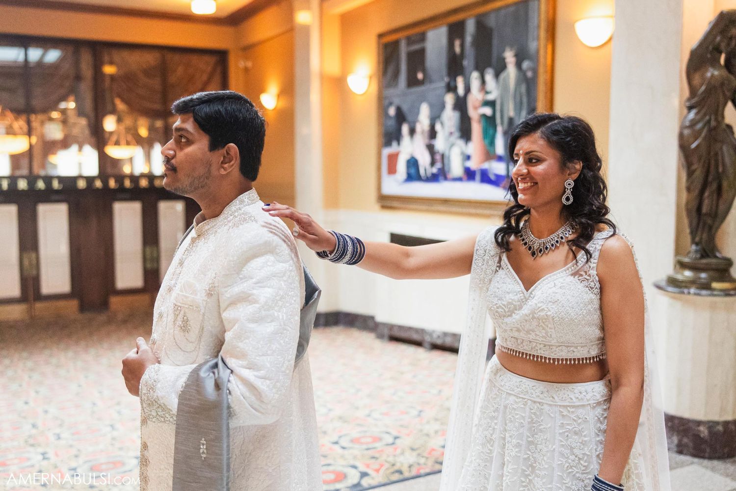 A couple participates in a traditional first look moment at their wedding in an elegant indoor venue.