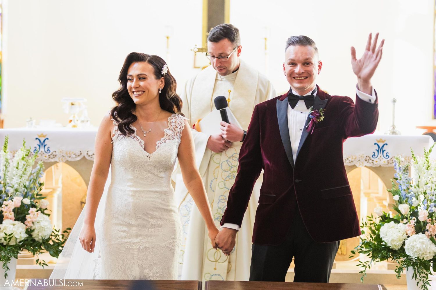 A joyful couple celebrates during their wedding ceremony at the altar decorated with white flowers.