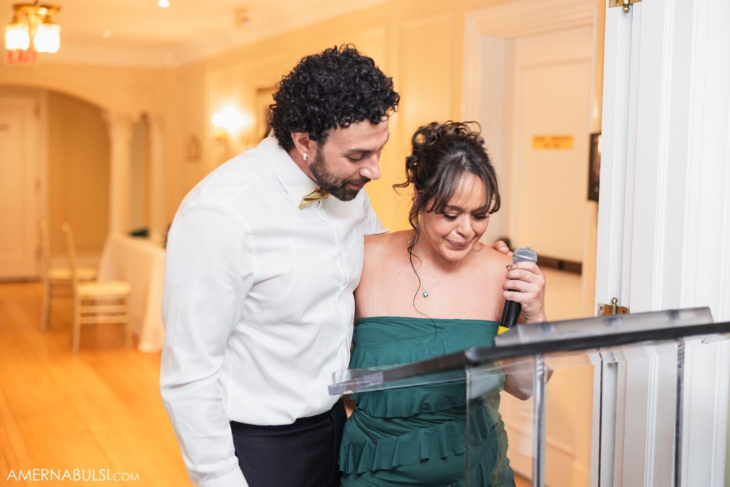Couple looking at something together in an elegant hallway with warm lighting.